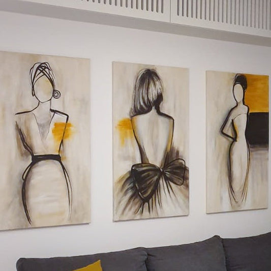 Set de picturi 3 bucati cu 3 figuri feminine realizate manual in vopsea acrilica in stil abstract pe fundal crem cu contur negru si accente ocru in context de amenajare moderna